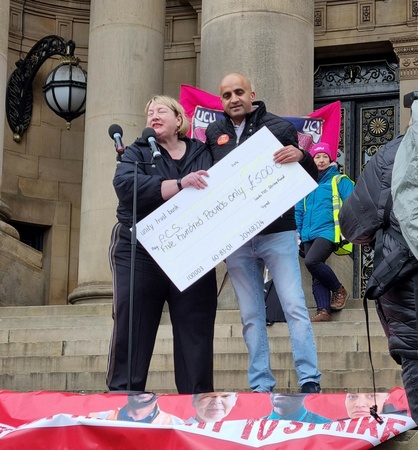 Photo shows a woman and a man holding a large cheque made out to PCS for £500