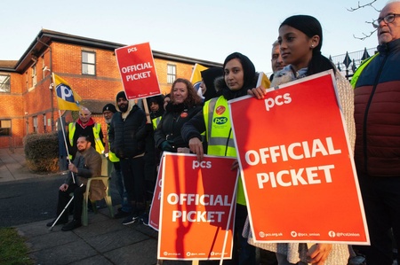 A row of PCS members holding OFFICIAL PICKET placards and PCS flags