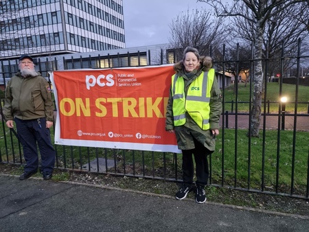 Two PCS members with PCS ON STRIKE banner outside a jobcentre