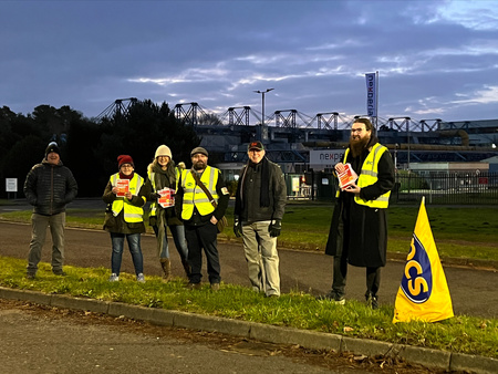 6 pickets standing in the dark with fluorescent vests and PCS flag