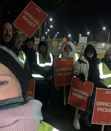 Selfie shot of 6 PCS members in the dark with PCS ON STRIKE placards