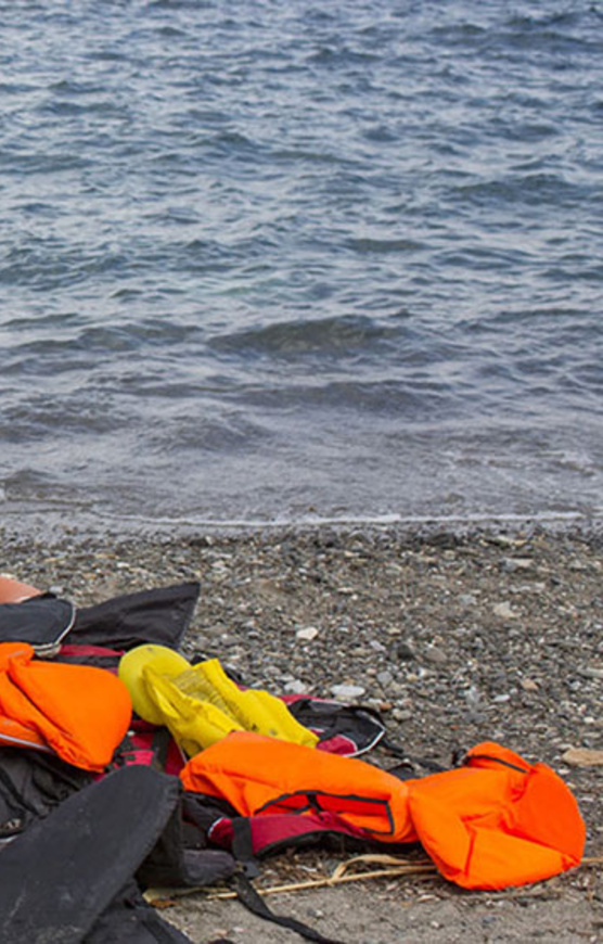 The photo shows some life jackets on a beach near a partially deflated raft.