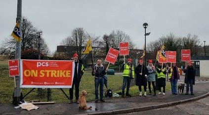 Image shows row of PCS pickets with PCS ON STRIKE banner and 2 dogs