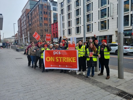 Image shows large group of PCS strikers behind a PCS ON STRIKE banner