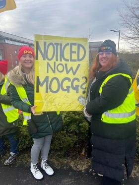 Image shows two women holding a placard that reads "NOTICED NOW MOGG?"