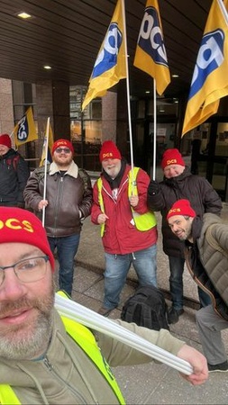 Image shows 5 pickets wearing PCS red beanie hats and holding PCS flags