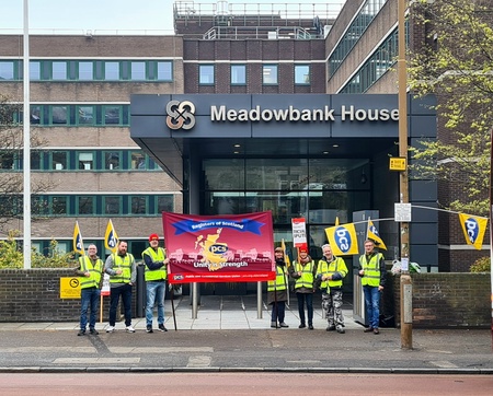 8 members with large banner outside Meadowbank House