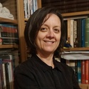 Susete has short dark hair and is standing in front of a bookcase