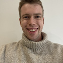 Finn has short hair and is wearing a jumper and a Palestine Solidarity badge.