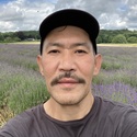 Evga is wearing a baseball cap and standing in front of a field of lavender
