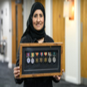 Nasrin is wearing a hijab and holding a frame containing 7 war medals