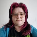 Alida has long, dyed pink hair and wears glasses