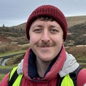 Aled is standing outside wearing a wooly hat and coat