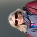 The photo shows rep and PCS Samba Band member Tracy Kelly who has long blond hair and is wearing sunglasses, a grey scarf and a maroon jacket.
