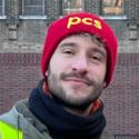 Carlos is on the picket line outside Tate Modern and is wearing a red PCS woolly hat and high viz jacket