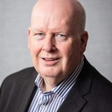 The photo shows Tony McMullan who is wearing a jacket and a shirt which is open at the collar.